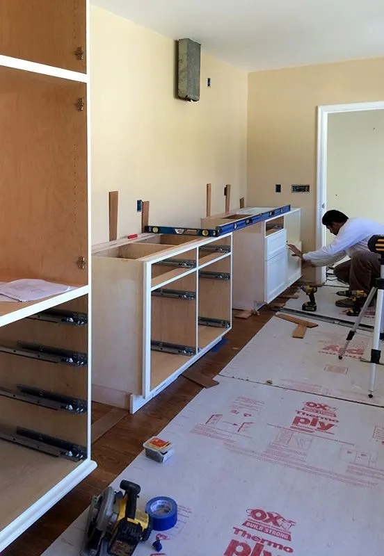 A man is working on a cabinet in a room.