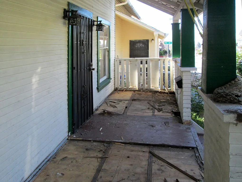 A porch with a green railing and a black door