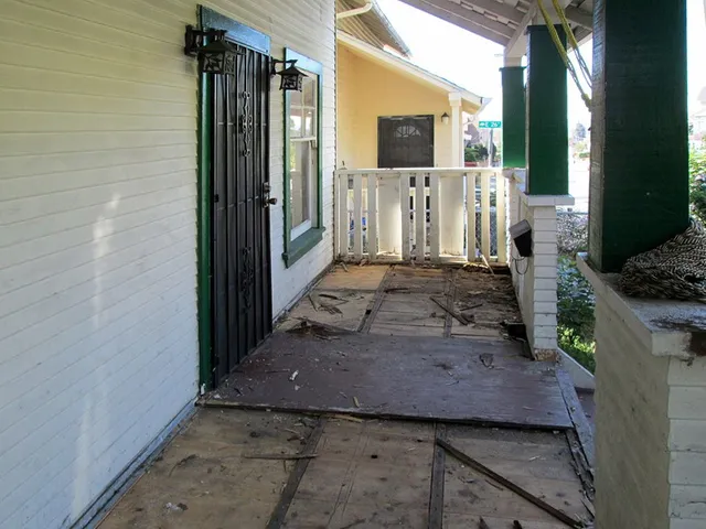 A porch with a green railing and a black door