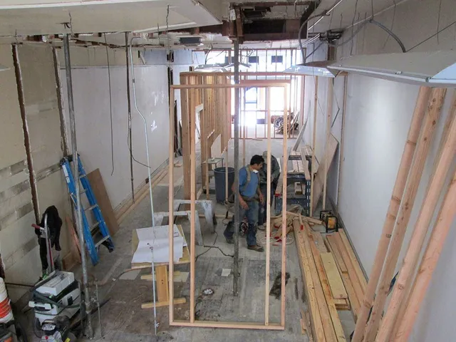 A man in a blue shirt is sitting in a room under construction