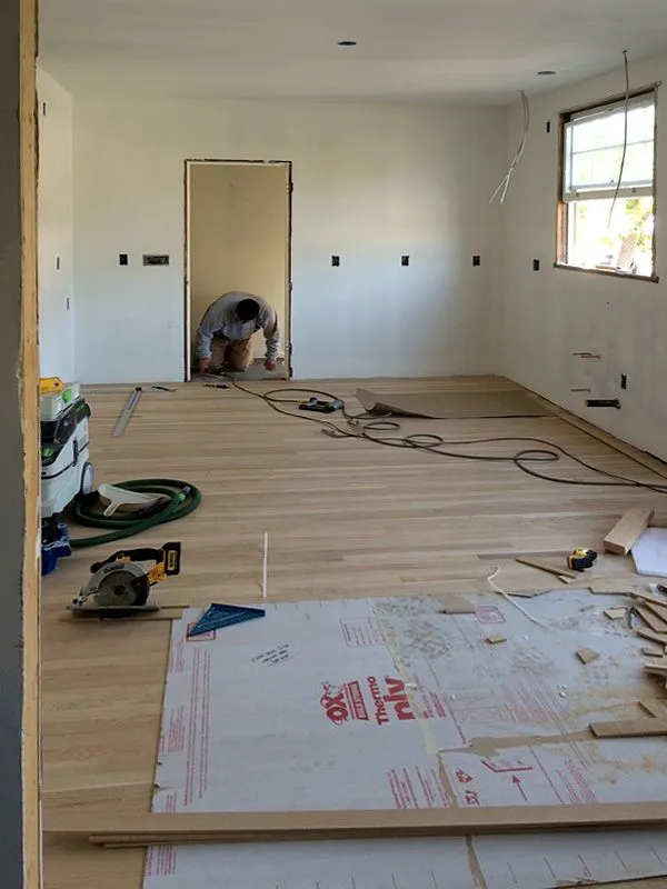 A man is working on a wooden floor in a room