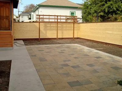 A backyard with a wooden fence and a patio