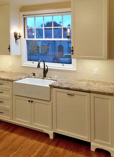 A kitchen with white cabinets and a sink under a window