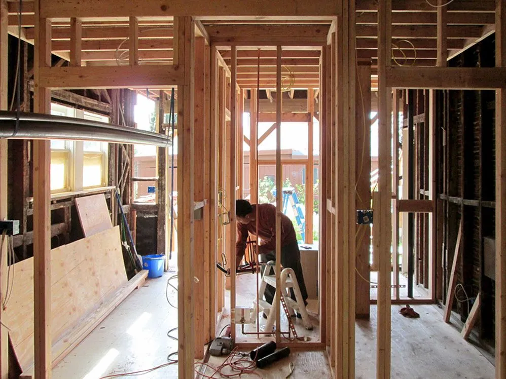 A man is working on a wooden frame of a house.