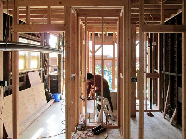 A man is working on a wooden frame of a house.