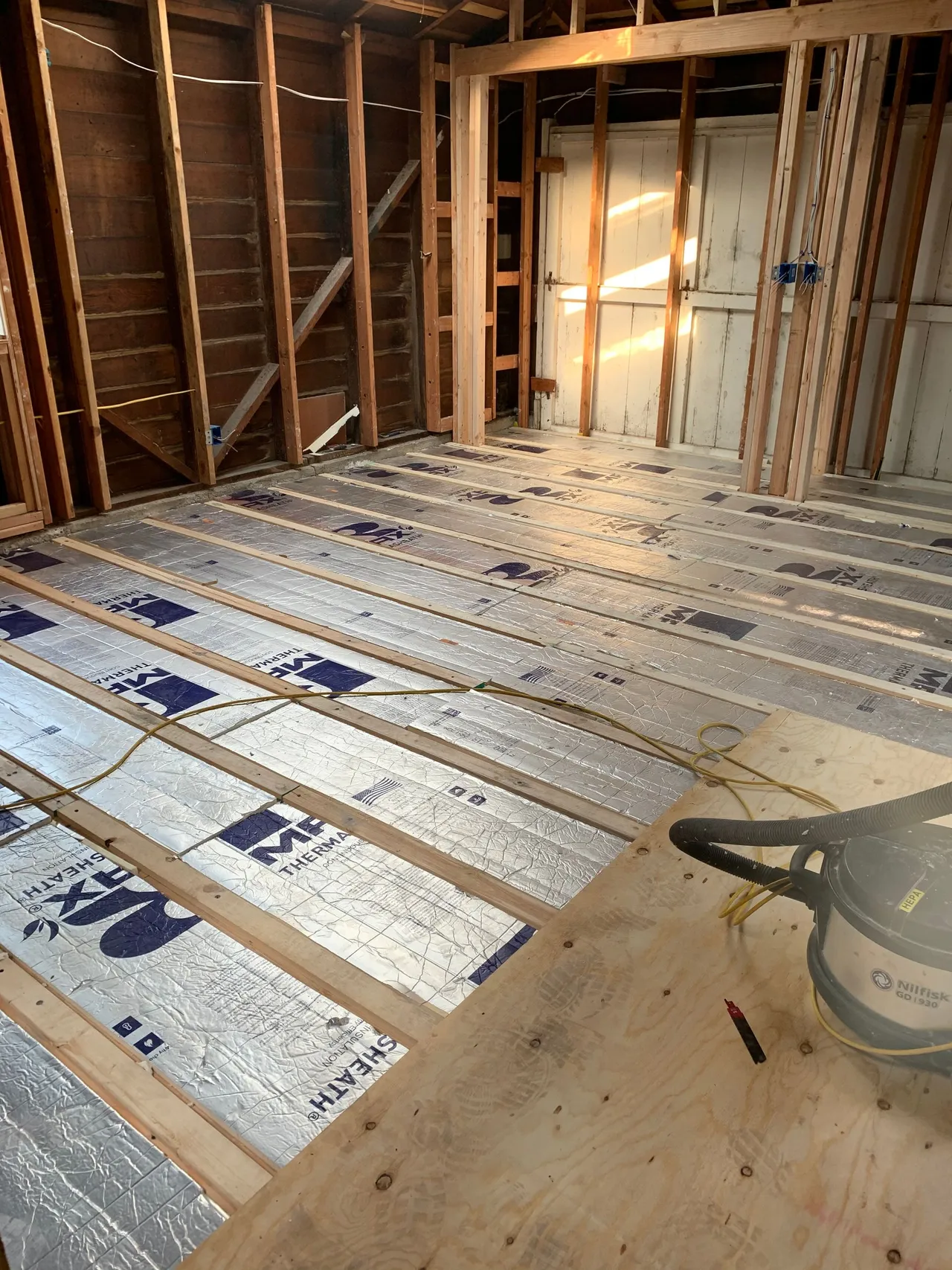 Partially insulated house interior with exposed framing and subfloor under construction