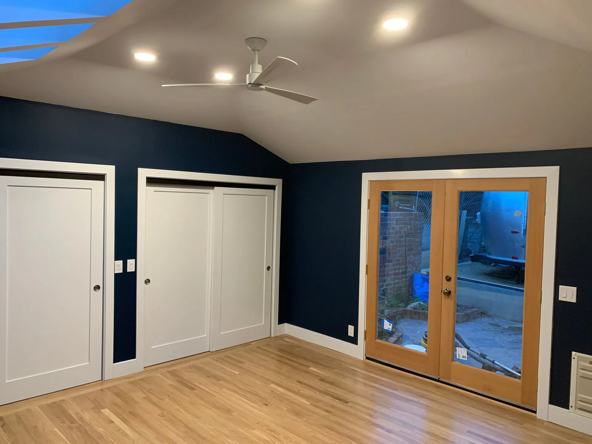 Blue-walled room with hardwood floor, white closet doors, and sliding glass doors to outside.