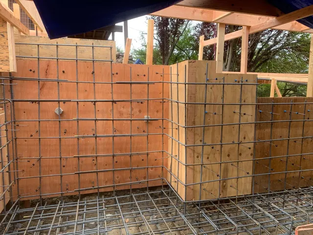 Rebar and plywood forms for concrete walls and floor slab at a construction site