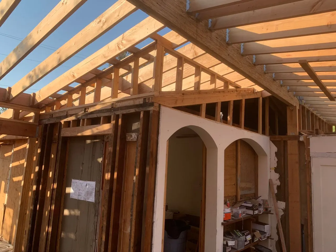 Partially built room with exposed wooden roof beams and white arched shelving under construction