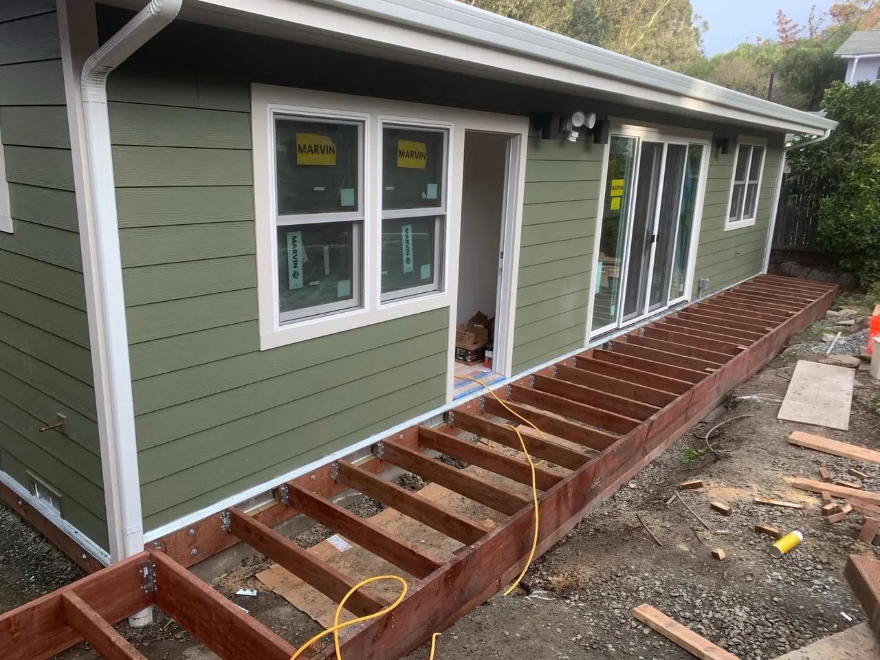 House exterior with green siding and a partially built wooden deck under construction