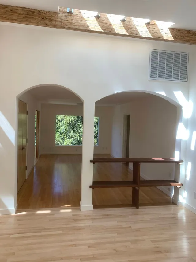 Bright loft with arched openings, wood floors, skylight, and a half-wall railing overlooking a lower level