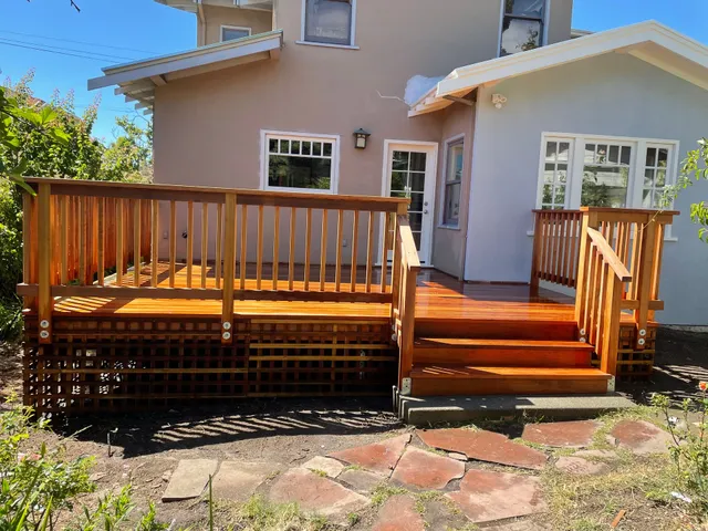Backyard wooden deck with steps leading to a beige house and sliding glass door