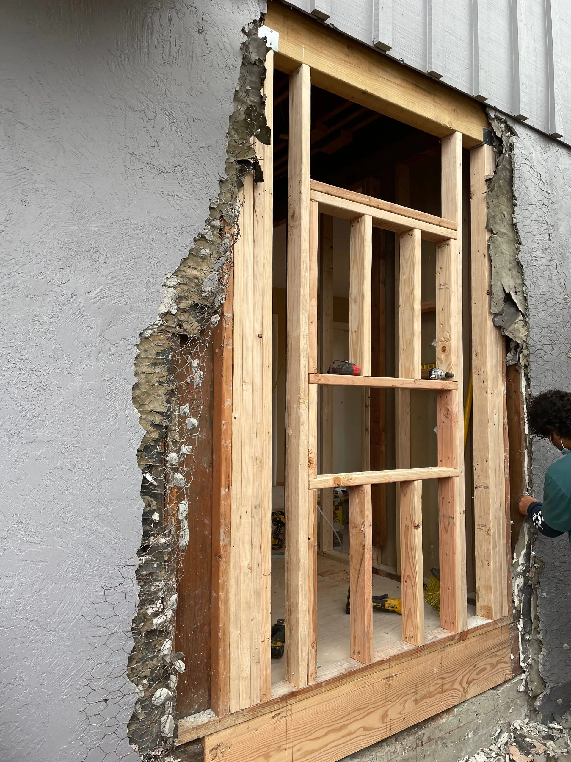 Partially framed doorway in a gray wall with exposed wood and plaster during construction