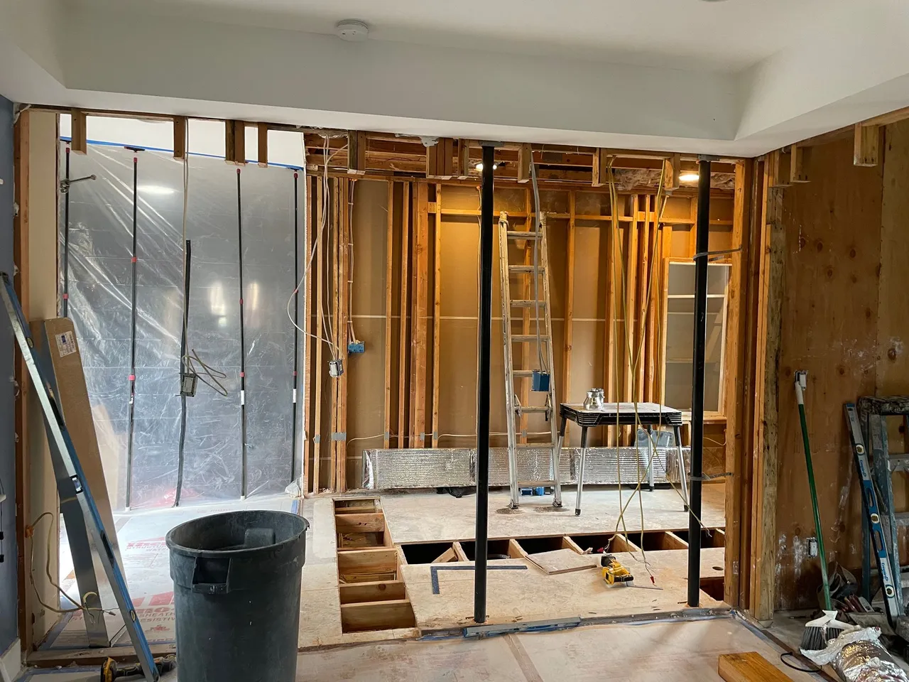 Renovated room with exposed studs, tools, and a partially removed wall in progress