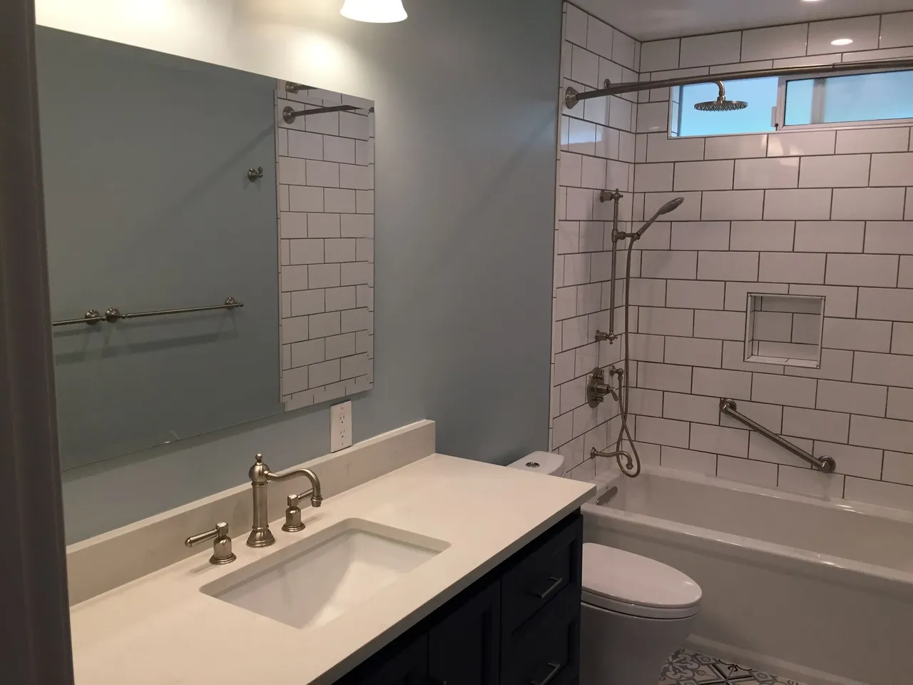 Modern bathroom with white vanity, large mirror, subway tile shower, and toilet visible