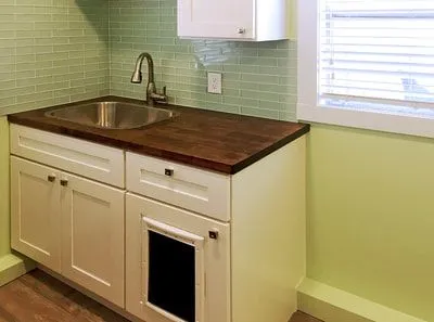 A kitchen with a sink , cabinets , and a window.