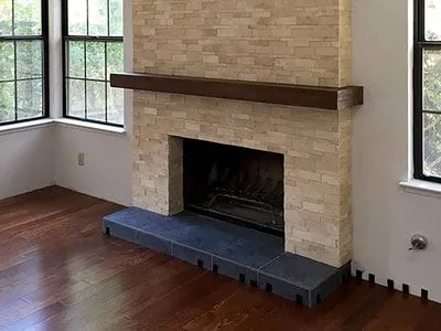 A living room with a fireplace and two windows.
