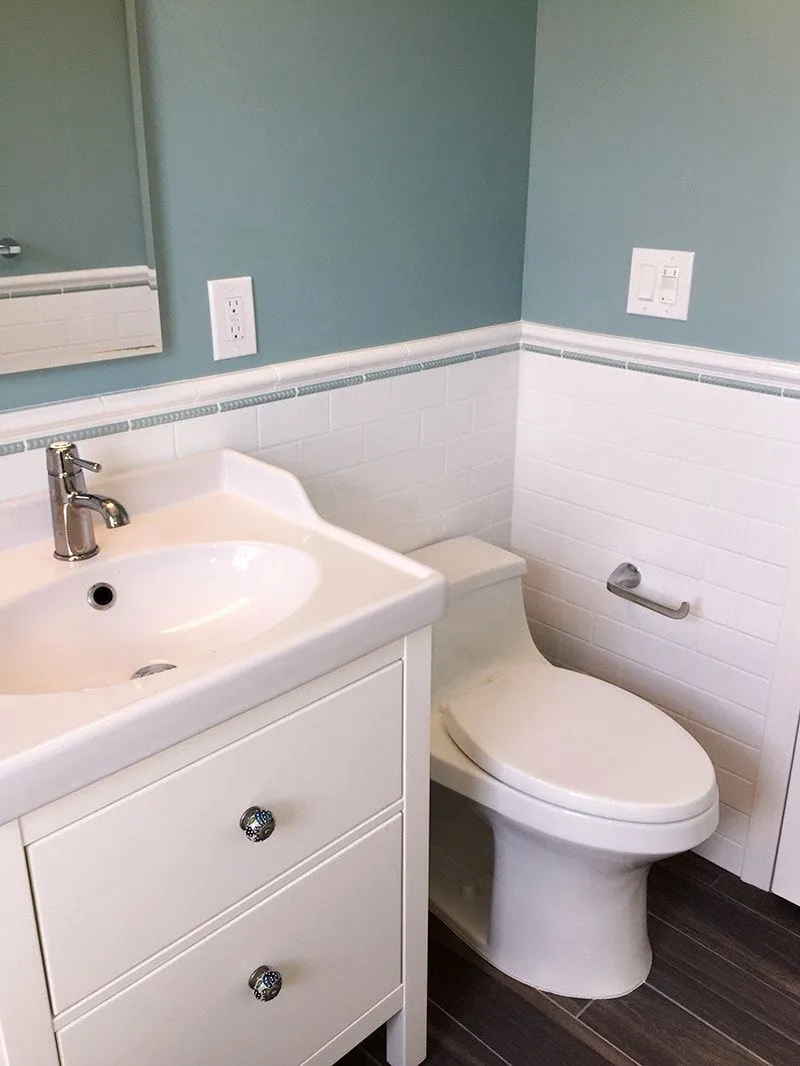 A bathroom with a toilet , sink and mirror.