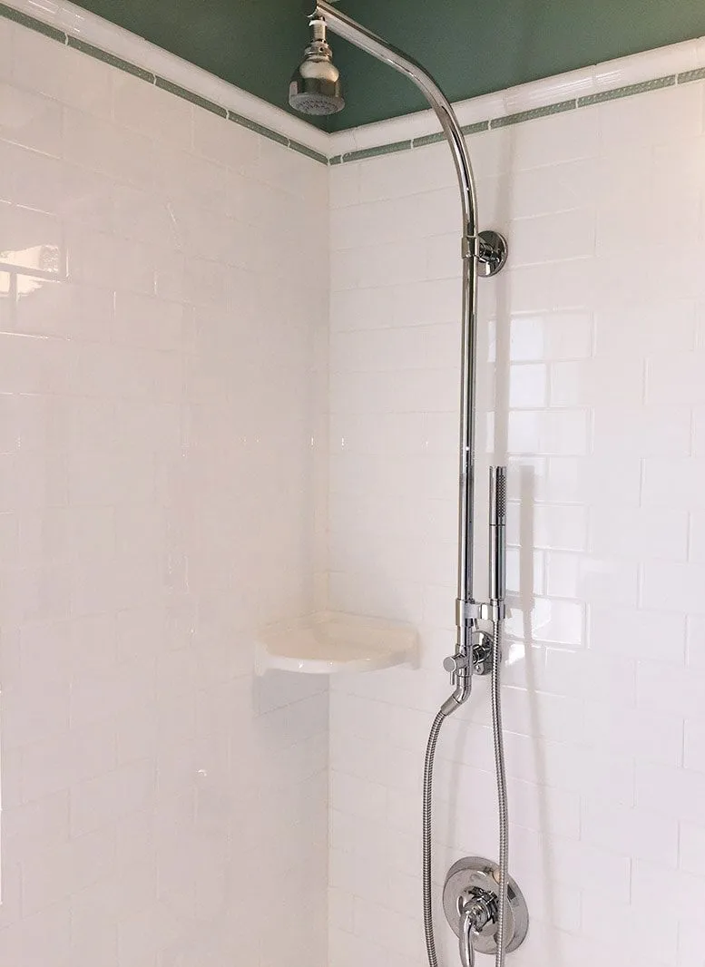 A shower head is hanging from the ceiling in a bathroom.