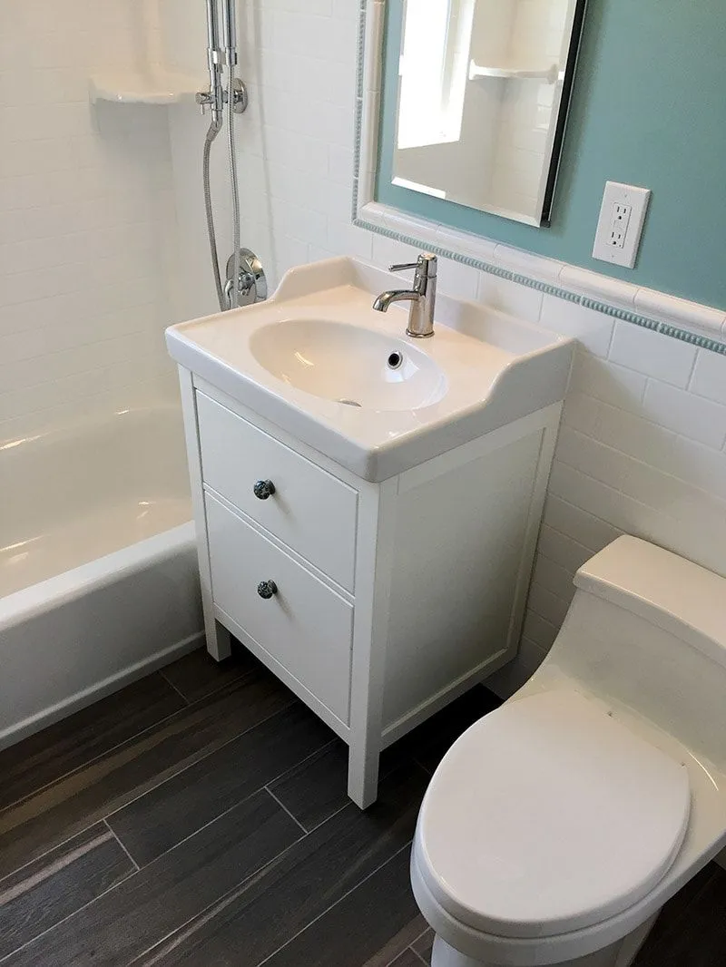 A bathroom with a toilet , sink , tub and mirror.
