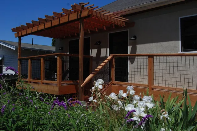 A house with a wooden deck and flowers in front of it