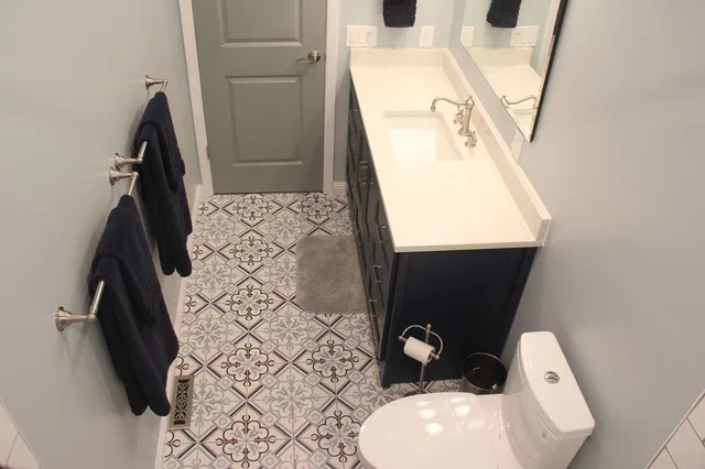 A bathroom with a toilet , sink and mirror.