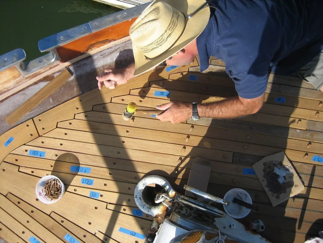 A man wearing a cowboy hat is working on a boat